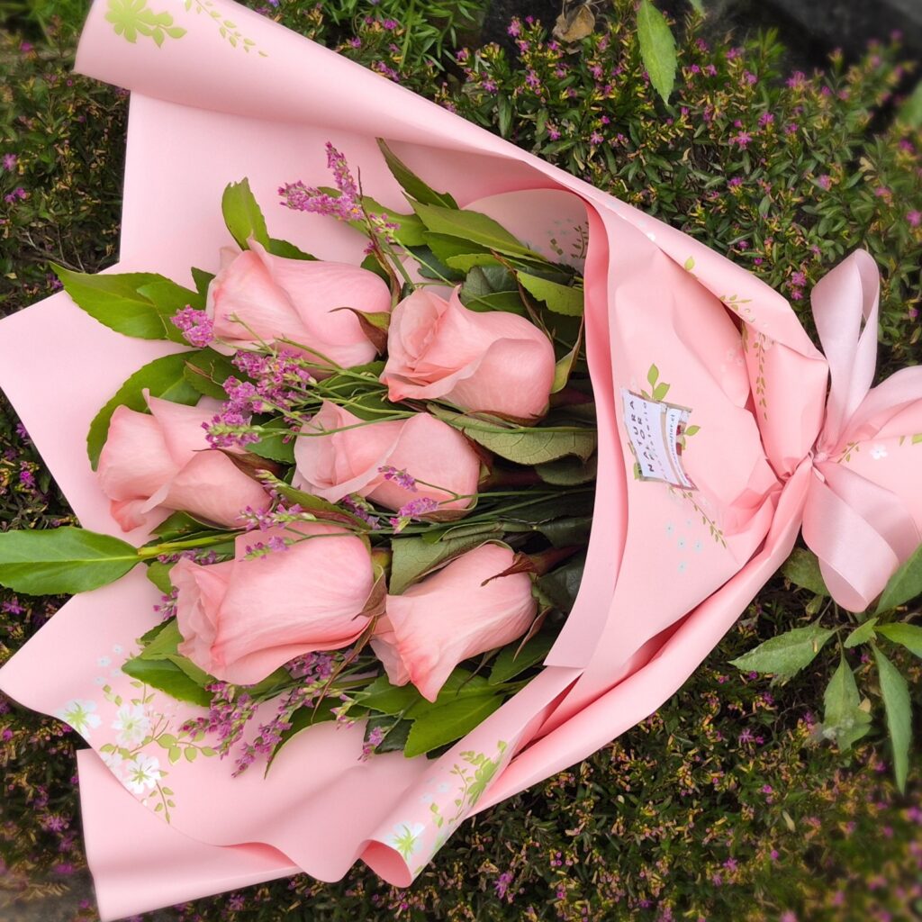 "Delicado ramillete de 6 rosas rosadas frescas envueltas en papel rosado con cinta. Servicio de flores a domicilio en Concepción por Naturaflor."